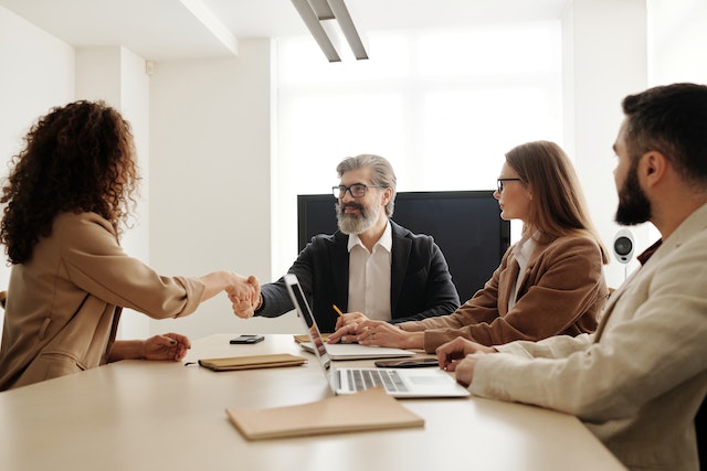 Client meeting with a team of property managers in a conference room and shaking hands