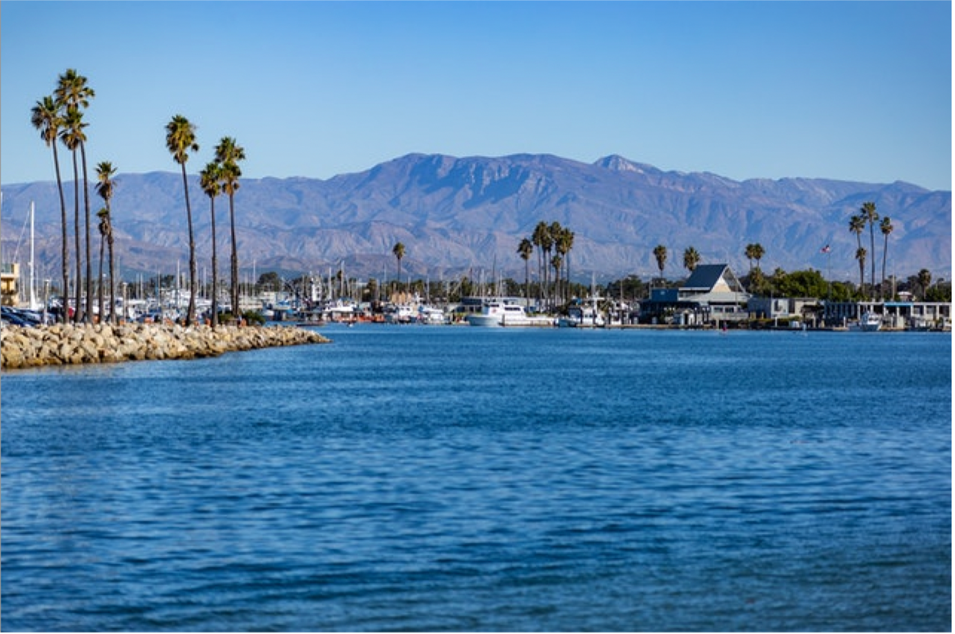 ocean view with palm trees one the shores and mountains in the background