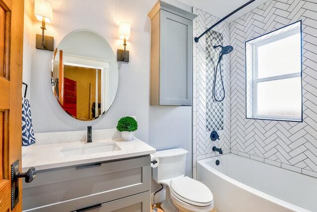 bathroom with which counters round mirror and small window