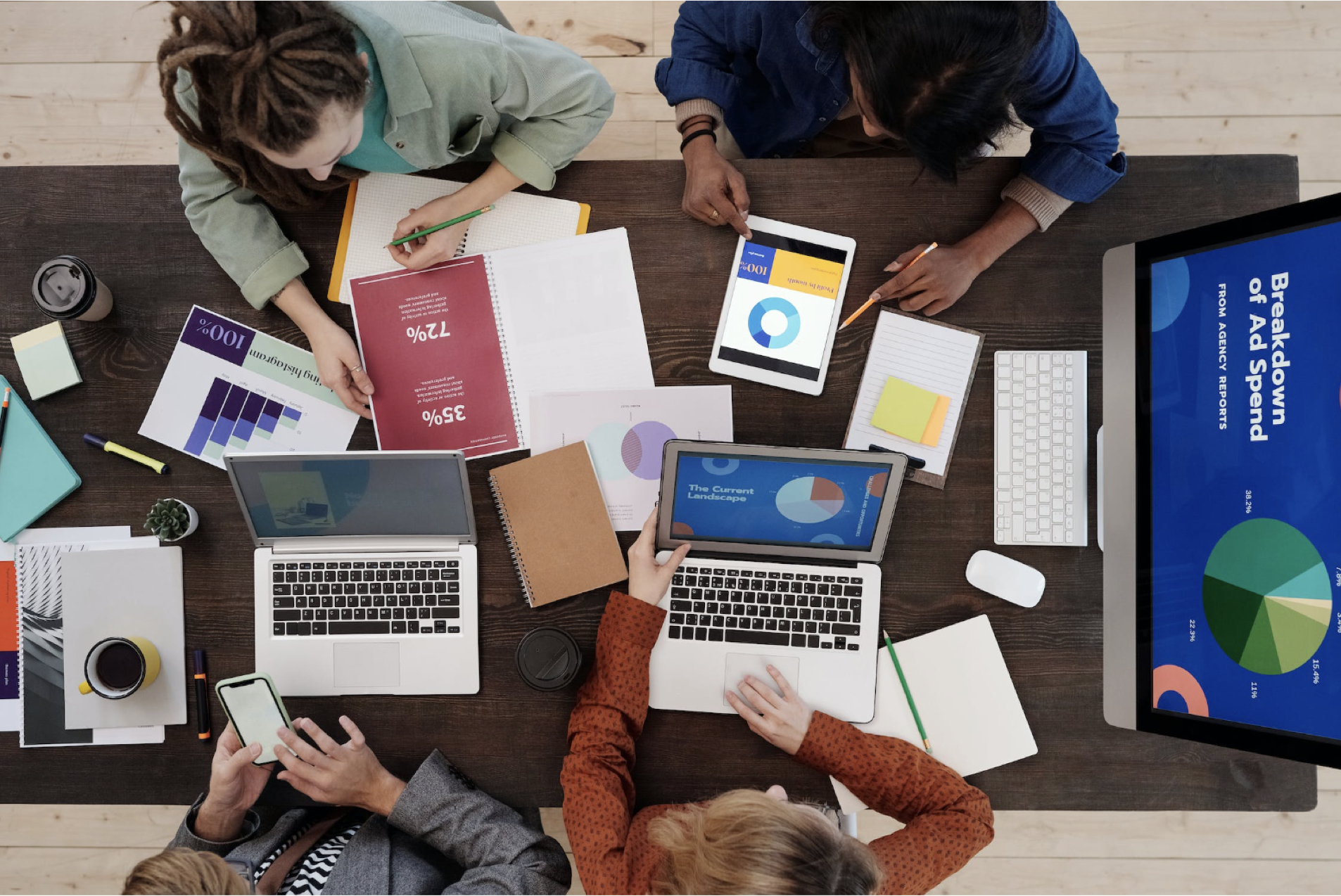 four marketing associates looking over stats and projections on their tablets and computers