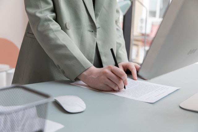 person in a gray suit jacket working at a computer desktop