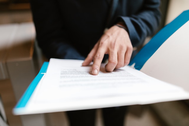 person pointing at a section of a document in a blue folder