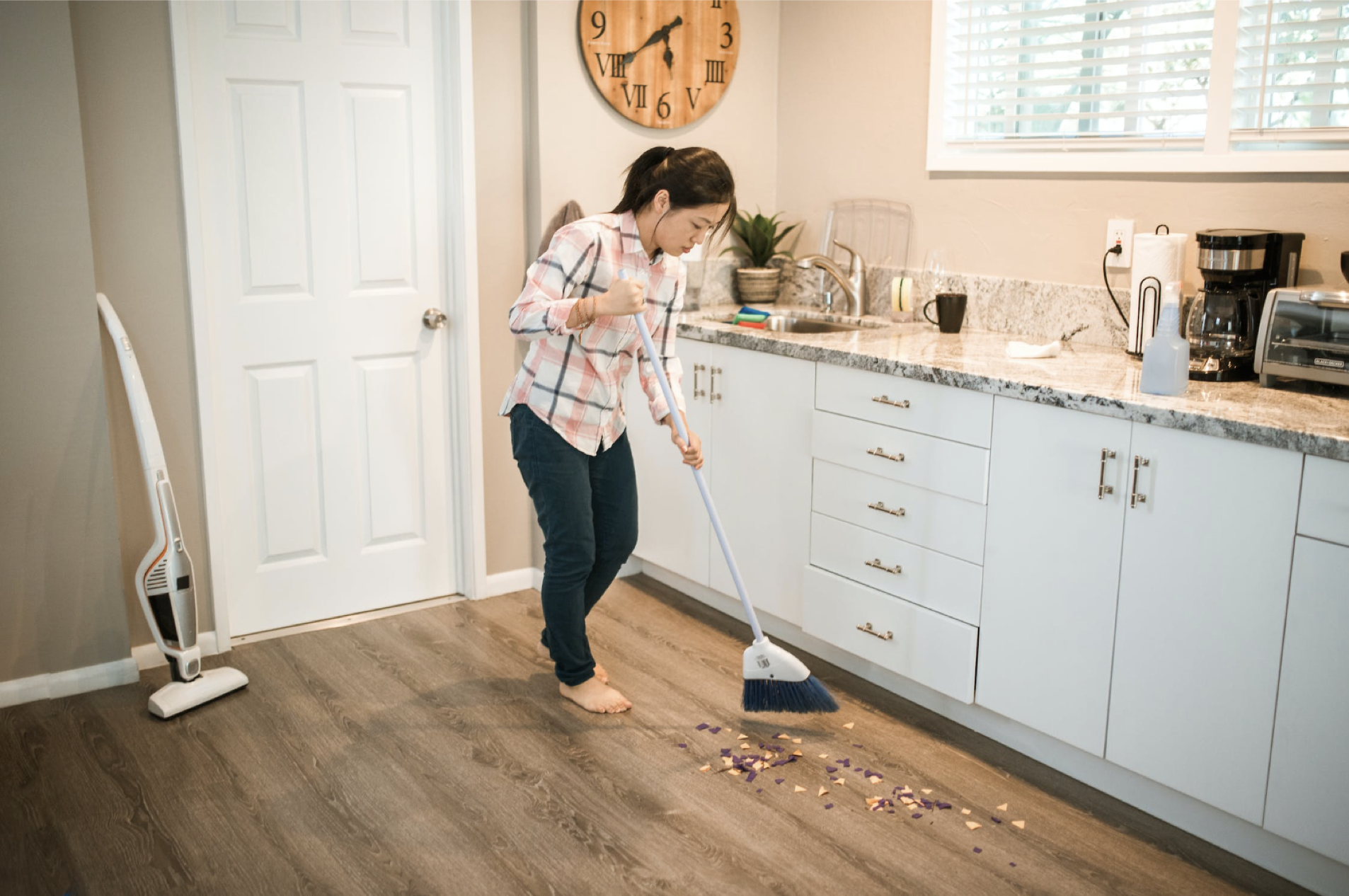 person sweeping the floor in their kitchen