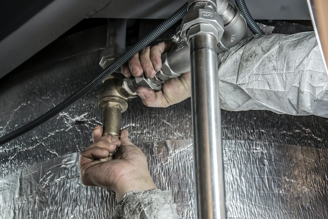 plumber tightening attachments connecting two pipes together