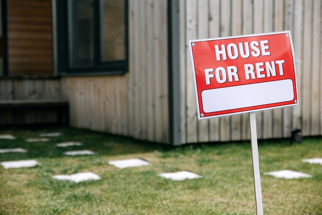 red sign in front of a house that says house for rent