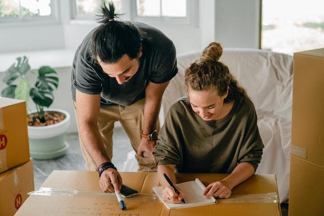 two people writing on a moving box